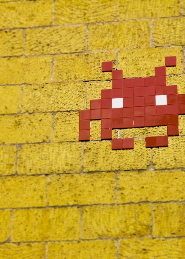 Orange space invader on a yellow wall.