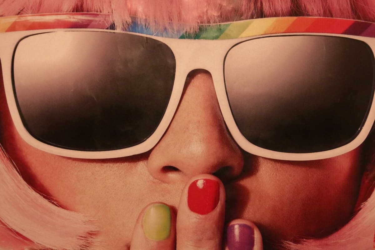 Closeup of woman in sunglasses showing eyes, nose, and fingers over mouth.